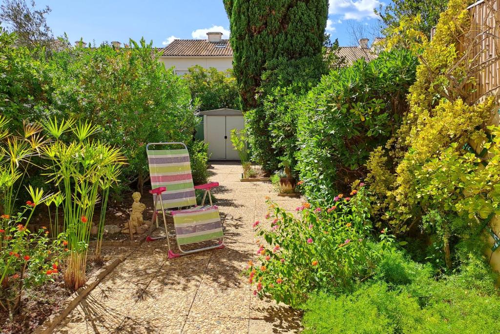 un jardin avec une chaise et quelques buissons dans l'établissement LES PINEDES - Un jardin fleuri à côté de la plage, au Grau-du-Roi