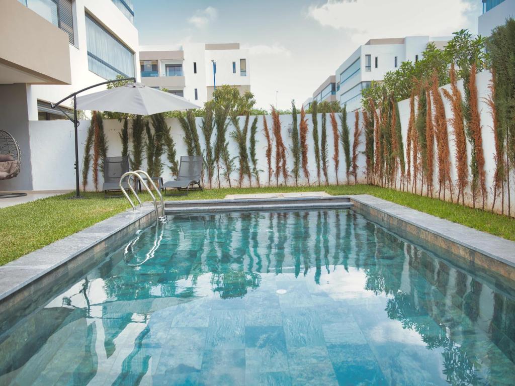 a swimming pool in a yard with an umbrella at Sancy Luxury rez de jardin avec piscine privée in Casablanca