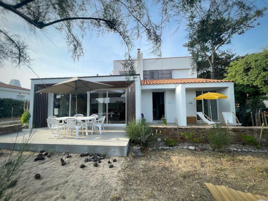 une maison avec une table, des chaises et un parasol dans l'établissement Villa cosy à deux pas de la plage - Classée 3 étoiles, à Les Sables-dʼOlonne