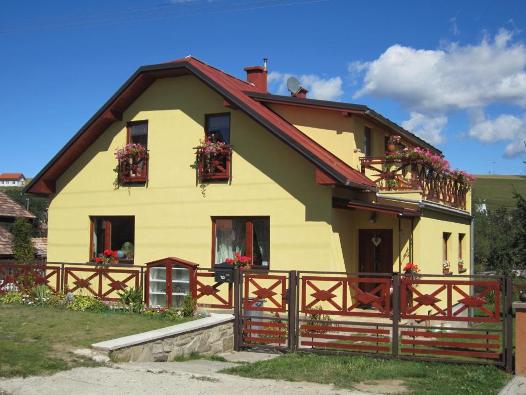 a yellow house with flower boxes on the windows at Privat Vrbov 23 in Vrbov