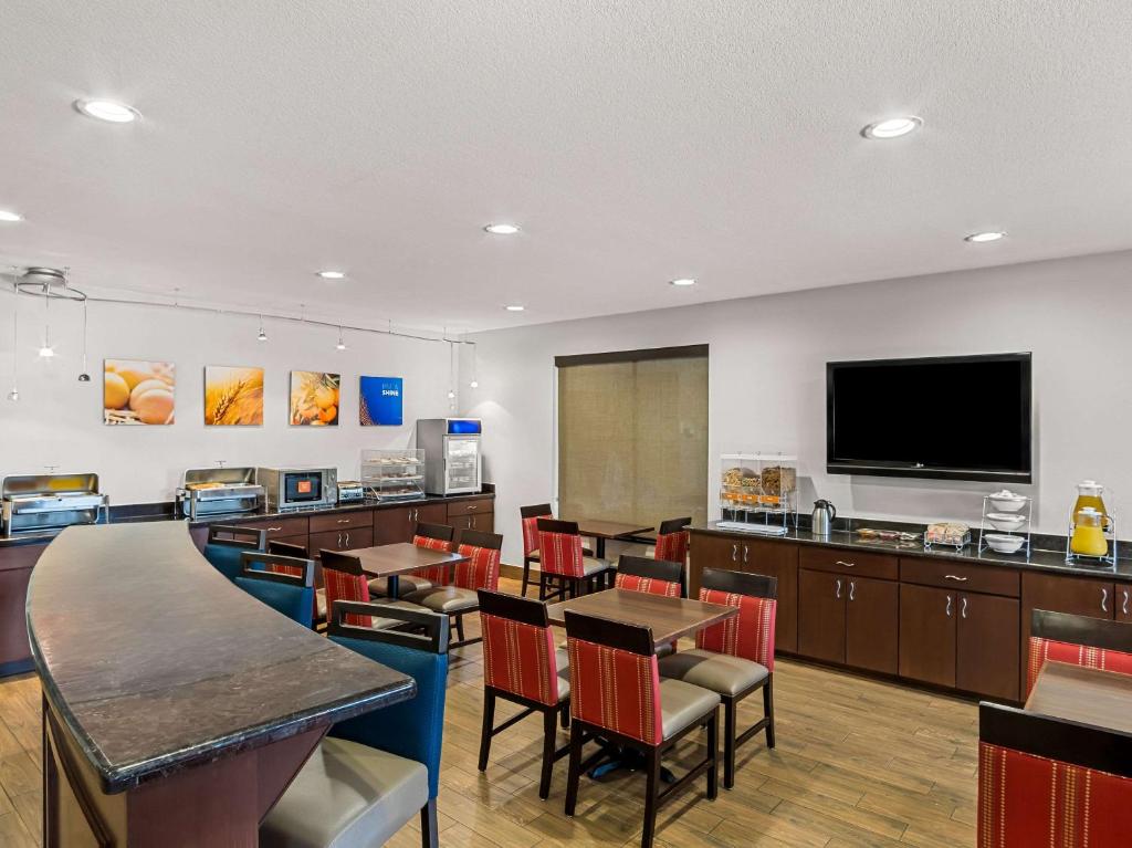 a restaurant with tables and chairs and a flat screen tv at Comfort Suites Lindale in Lindale