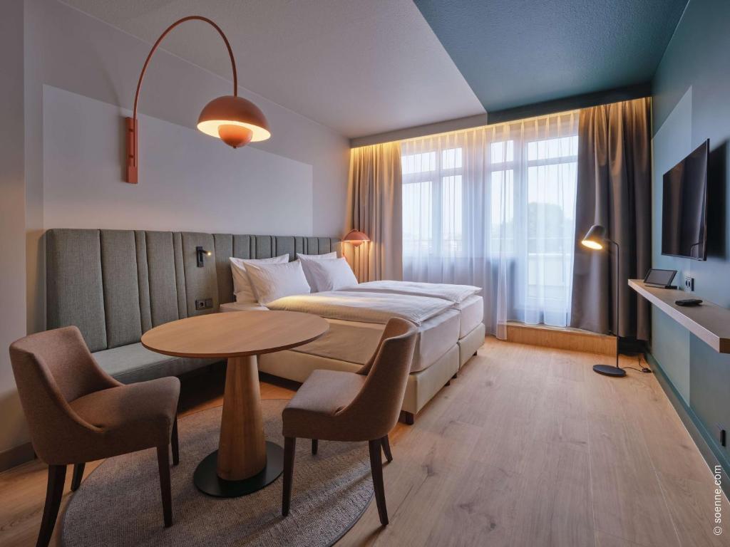 a hotel room with a bed and a table and chairs at Dorint Hotel Bonn in Bonn