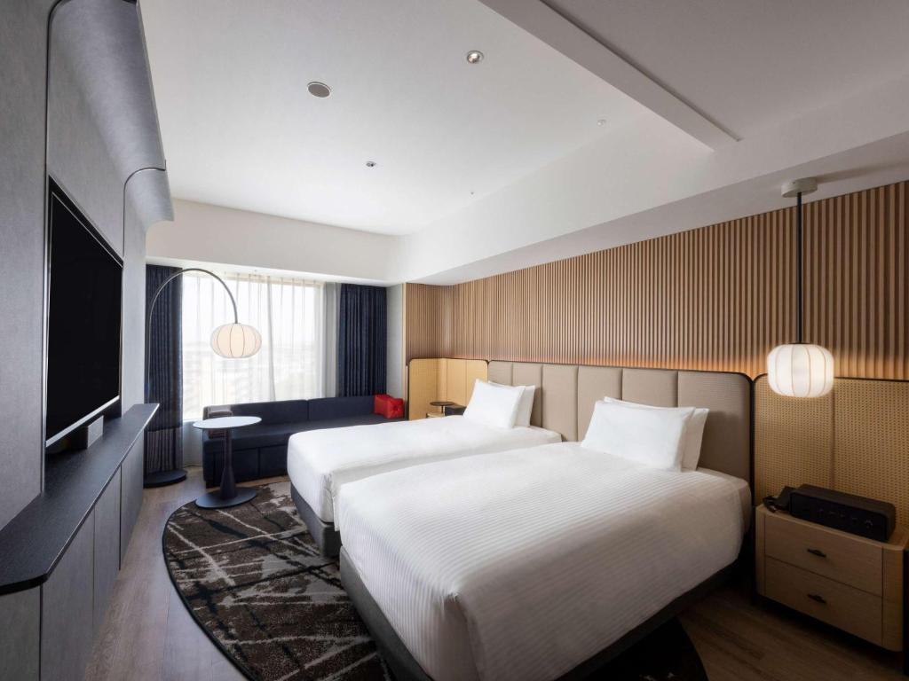 a hotel room with two beds and a television at Novotel Nara in Nara
