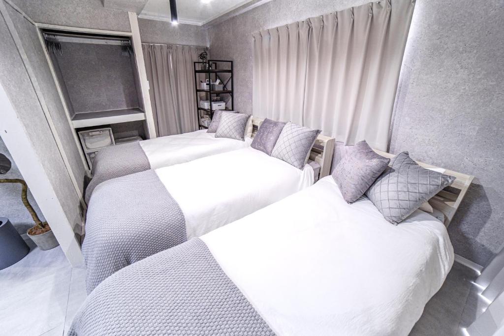 two beds in a bedroom with white and gray at 1 line to Asakusa! Modern Room, 5 mins walk from Togoshi-ginza Sta in Tokyo
