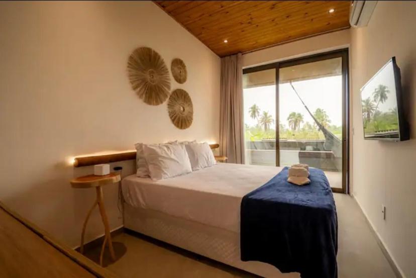 ein Schlafzimmer mit einem Bett und einem großen Fenster in der Unterkunft Vista Milagres in São Miguel dos Milagres