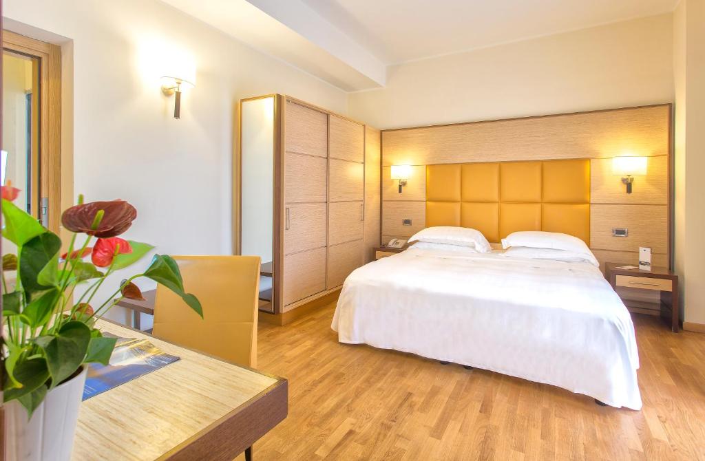a bedroom with a large white bed and a table at Virgilio Grand Hotel in Sperlonga