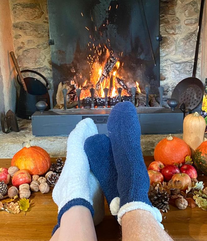 une personne en chaussettes bleues assise devant une cheminée dans l'établissement Ranch du Roc, à Monteils