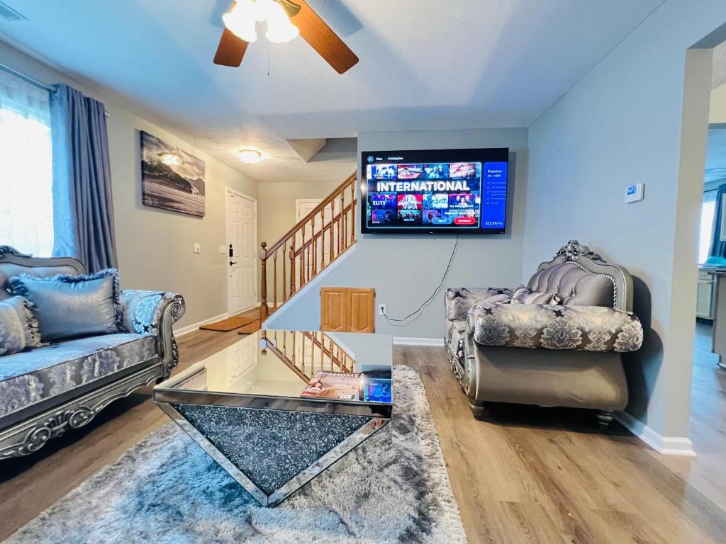 a living room with a couch and a tv on the wall at Find your home away from home in our delightful 4 bedroom space in Indianapolis