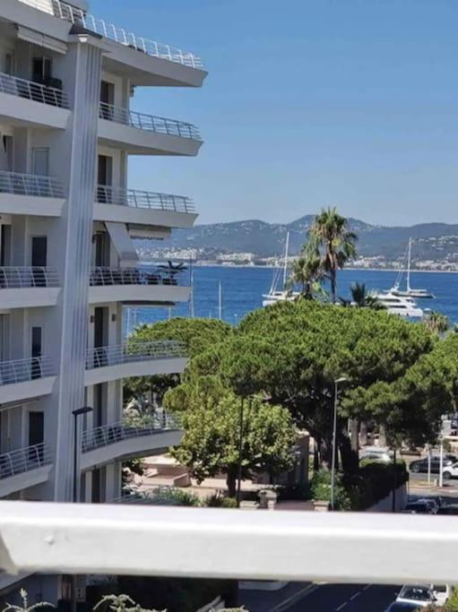 un grand immeuble d'appartements avec des arbres en face de l'eau dans l'établissement New top floor avec vue mer, Croisette à Palm Beach, à Cannes