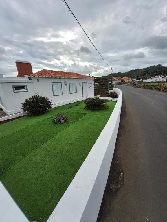 une maison avec une pelouse verte à côté d'une rue dans l'établissement Alojamento São Brás, à São Brás