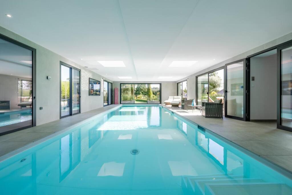a swimming pool with blue water in a house at Villa, piscine intérieure - Baie Mont Saint Michel in Le Petit-Celland