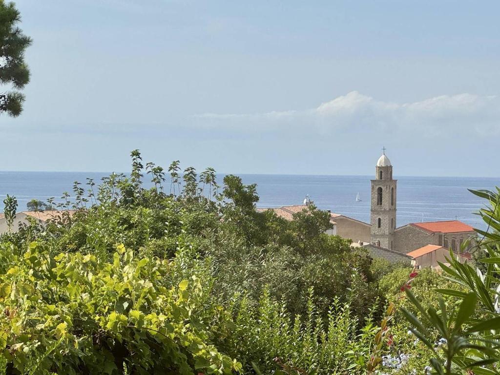 a church on a hill with the ocean in the background at Maison Les aloes - vue mer et proche centre ville in Propriano