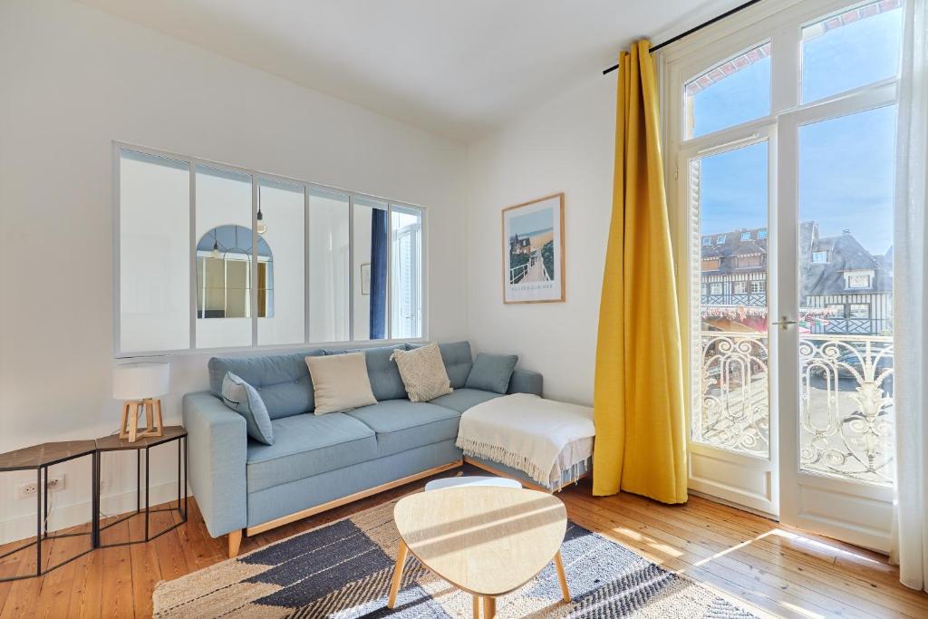 a living room with a blue couch and a window at Au bon air de Villers - plage à 200 mètres in Villers-sur-Mer