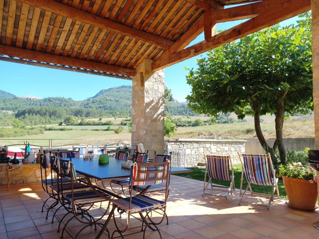 a patio with a table and chairs under a wooden pergola at La Fond de Mière in Lachau