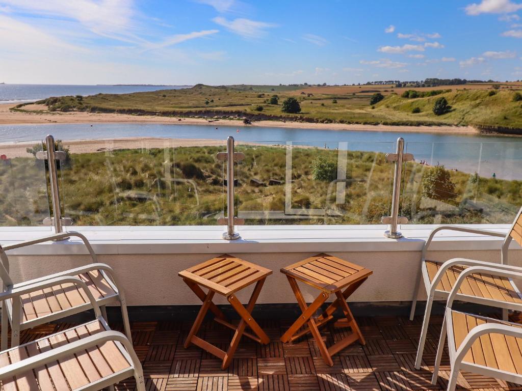 two tables and chairs on a balcony with a view of the water at Ocean View in Alnwick