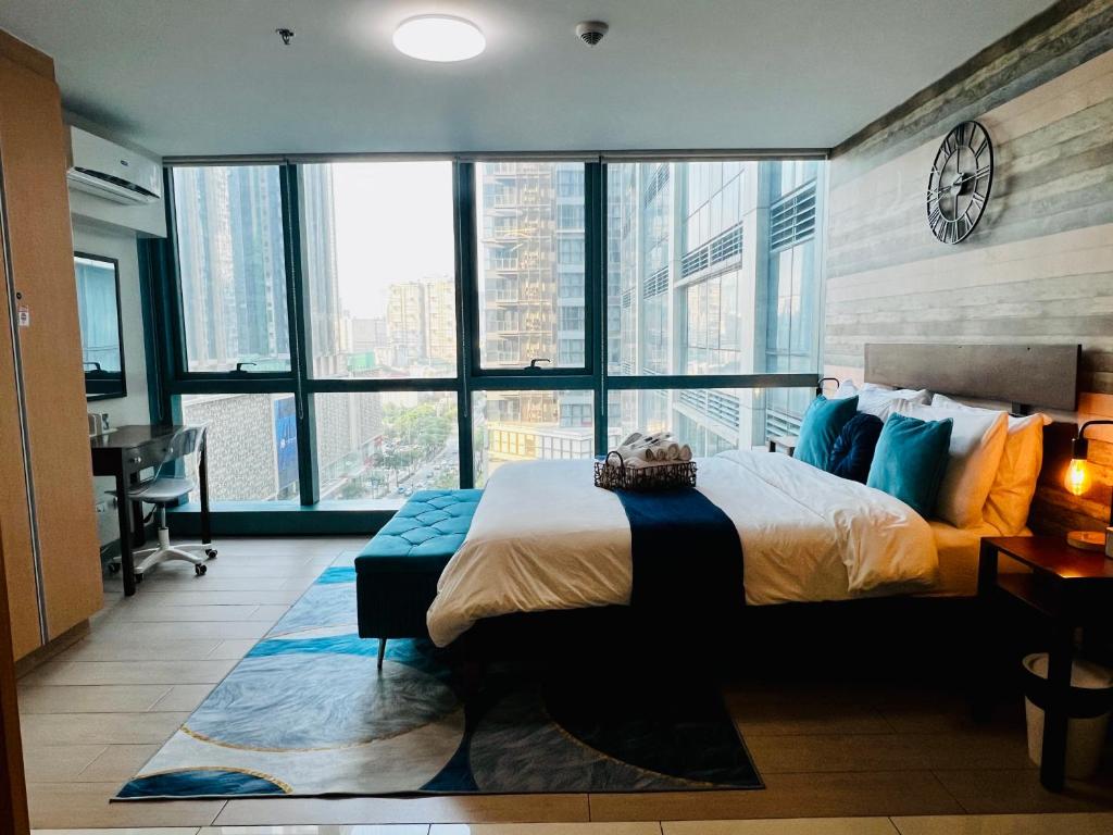 una camera da letto con un letto grande e grandi finestre di LUX BGC 1BR, Uptown Mall Connector, 5G WiFi, Pool, Ste 11 a Manila