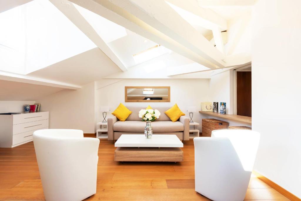 Elle comprend un salon doté d'un mobilier blanc et d'oreillers jaunes. dans l'établissement Luxurious StudioLoft 3 MINUTES FROM LA CROISETTE, à Cannes