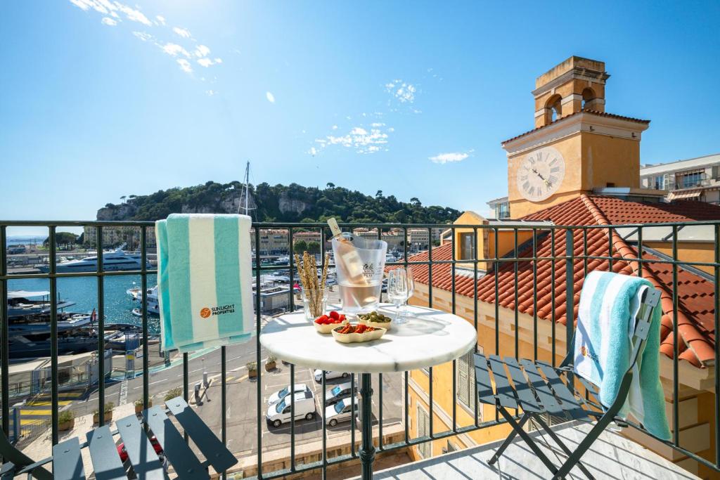 d'un balcon avec une table et une tour d'horloge. dans l'établissement Sunlight Properties - Capitaine 54 - 1 Bedroom, stunning holiday rental apartment with balcony and port view, à Nice