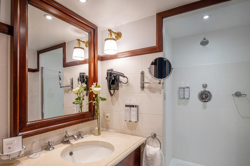 a bathroom with a sink and a mirror and a shower at Hotel Barsey by Warwick in Brussels