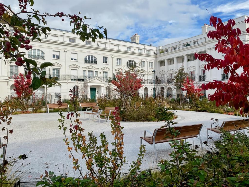 un grand bâtiment blanc avec des bancs devant lui dans l'établissement Suite Cartier Disneyland Paris - Rentaway BnB, à Serris