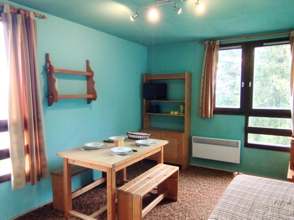 une chambre avec une table dans une pièce aux murs bleus dans l'établissement Studio cabine skis aux pieds, 5ème étage, Les Adrets-Prapoutel - FR-1-771-66, à Les Adrets