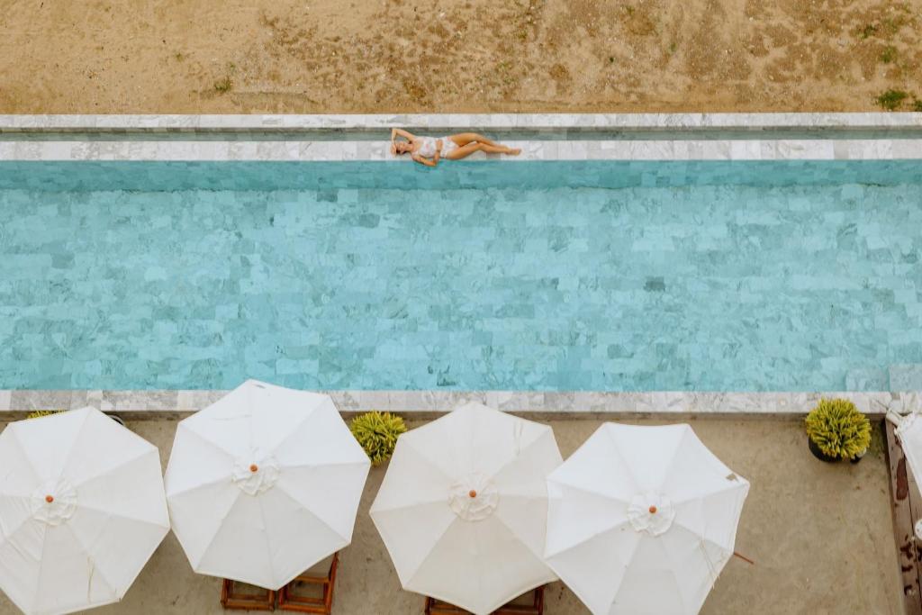 a group of white umbrellas next to a swimming pool at Elite Atoll Beachfront Hotel in Khanom