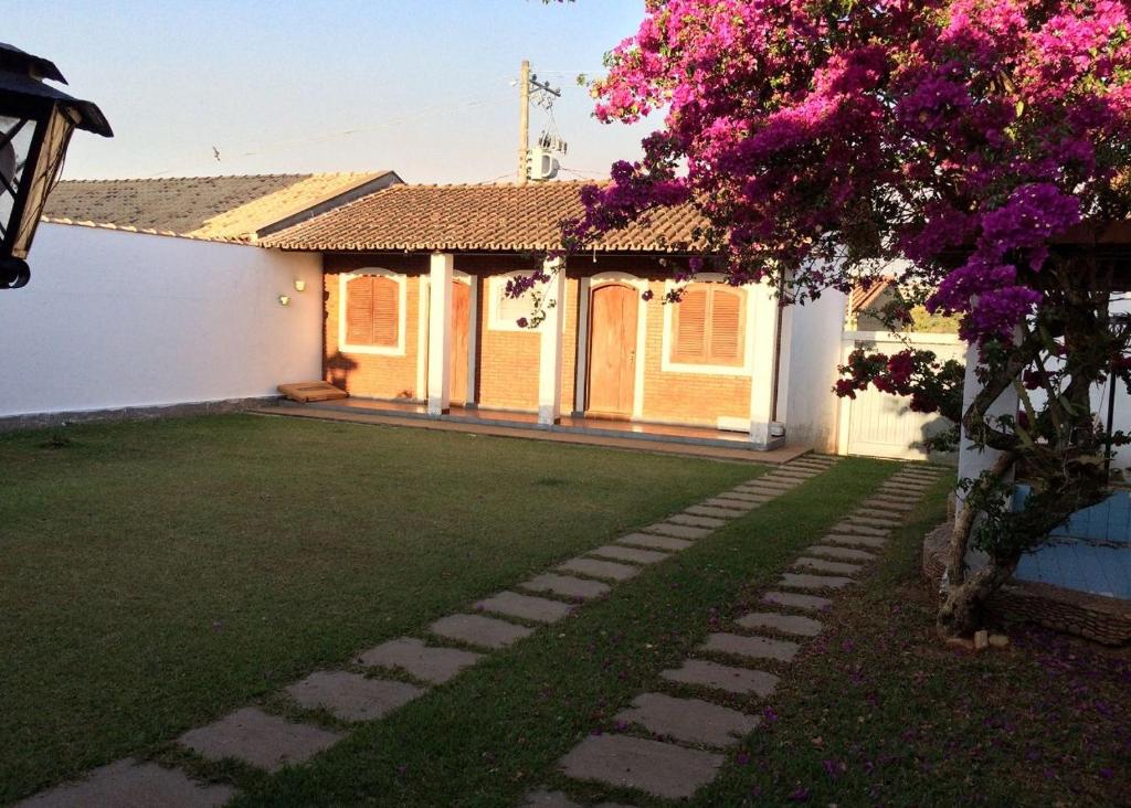 a yard with a house with a pink flowering tree at Pousada Casa da Vó Dita in Ouro Fino