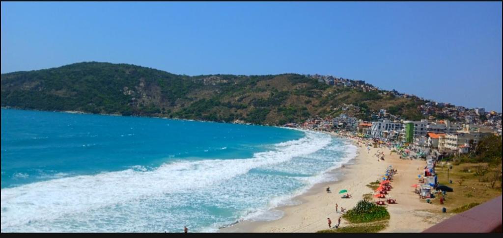 a beach with a bunch of people and the ocean at Sua casa na praia em Cabo Frio in São Pedro da Aldeia