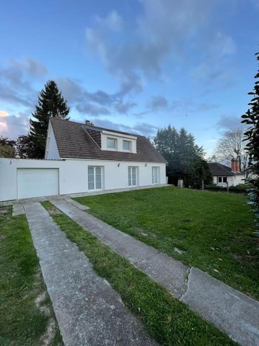 a white house with a grass yard and a driveway at Maison familiale et cosy in Argenteuil