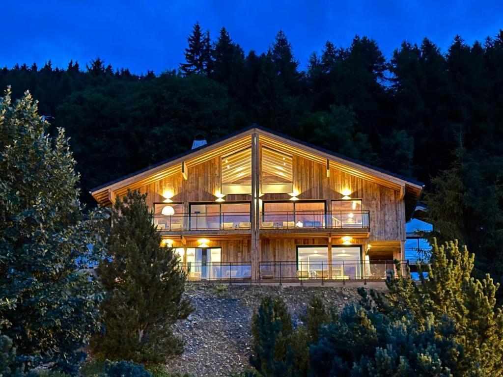 ein großes Holzhaus in der Nacht mit Bäumen in der Unterkunft Chalet luxe avec jacuzzi, sauna, 8 ch, La Plagne Montalbert - FR-1-181-2718 in Hermillon
