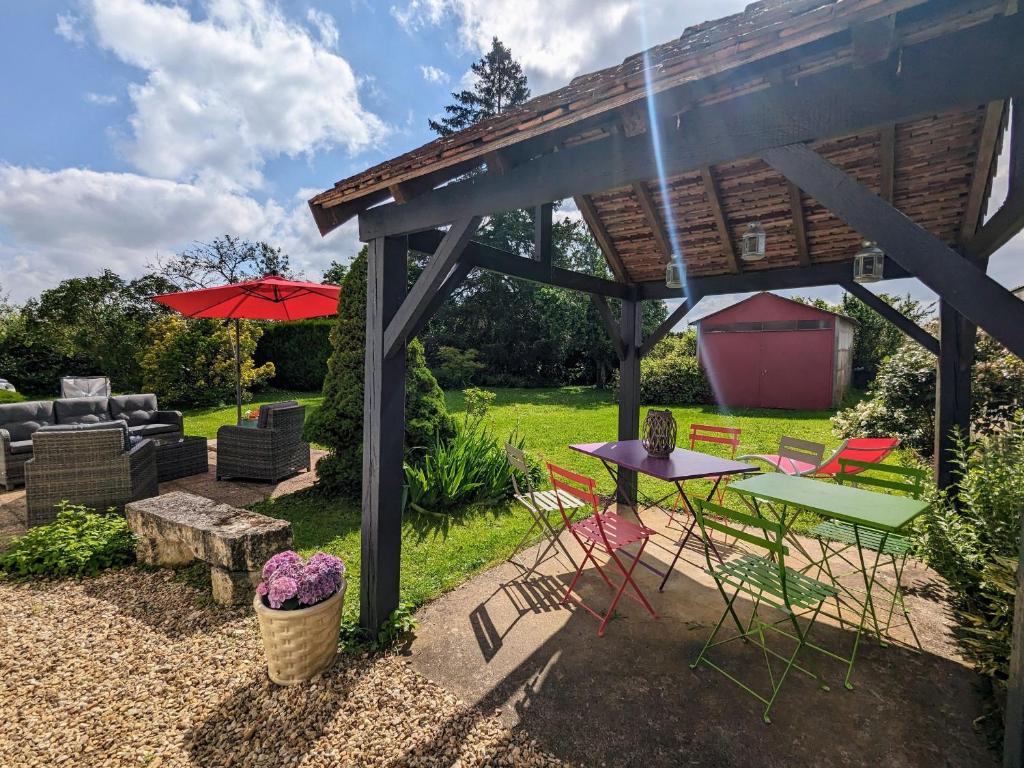 un patio con tavolo, sedie e ombrellone di Havre de paix en Berry avec jardin et cheminée - FR-1-591-616 a Brives