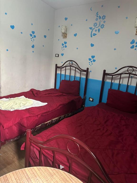 two beds with red sheets in a room at Hostal oasis in Cairo