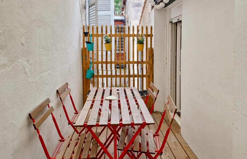 une table de pique-nique et des chaises sur un balcon dans l'établissement Fleuriau cozy boheme Proche marché & Vieux Port, à La Rochelle