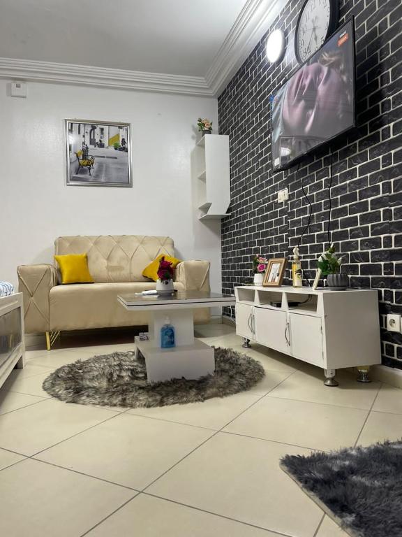 salon z kanapą i telewizorem na ceglanej ścianie w obiekcie Henock résidence w mieście Abidżan