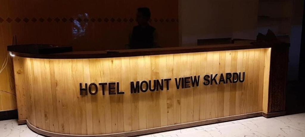 锡卡都Mount View Hotel Skardu的木制前台,上面写着酒店的话,看不到天空