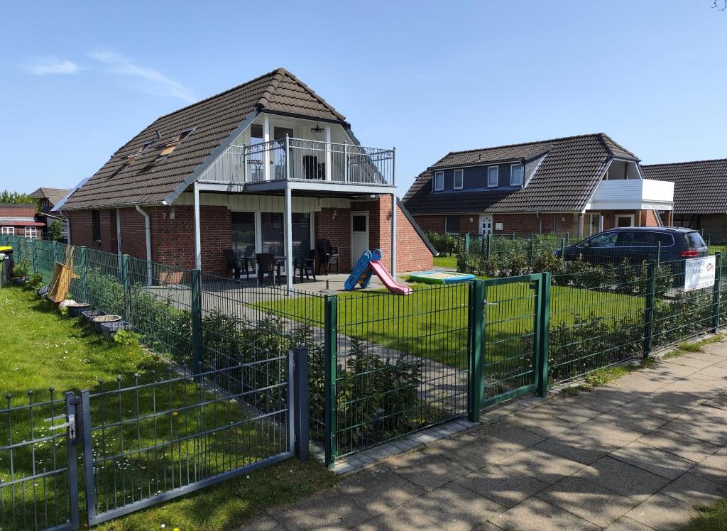 a person sitting on a fence in front of a house at Ferienhaus Krabbe, 8 Personen, 3-4 Schlafzimmer in Friedrichskoog