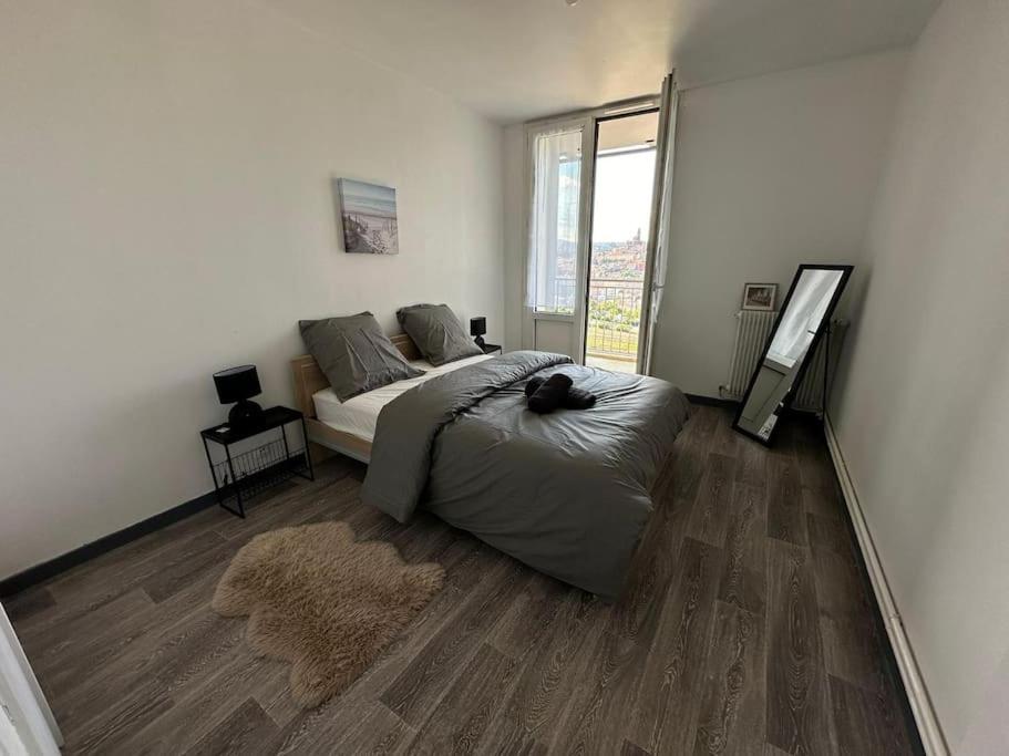 une chambre avec un lit et une grande fenêtre dans l'établissement Appartement T3 64m2 avec Balcon, vue sur le centre historique, WI-FI et PARKING GRATUIT, au Puy-en-Velay