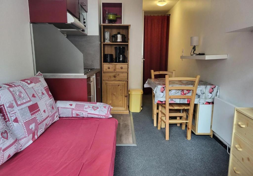 a small room with a pink bed and a table at Résidence Vanoise - VAL THORENS STUDIO 2 PERSONNES AU COEUR DE LA STATION ET SKIS AU PIEDS MAE-7806 in Val Thorens