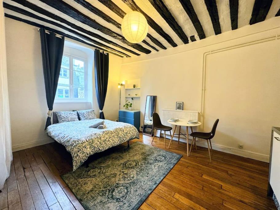 une chambre avec un lit, une table et des chaises dans l'établissement Charmant Appartement Parisien Près du Louvre Paris, France, à Paris
