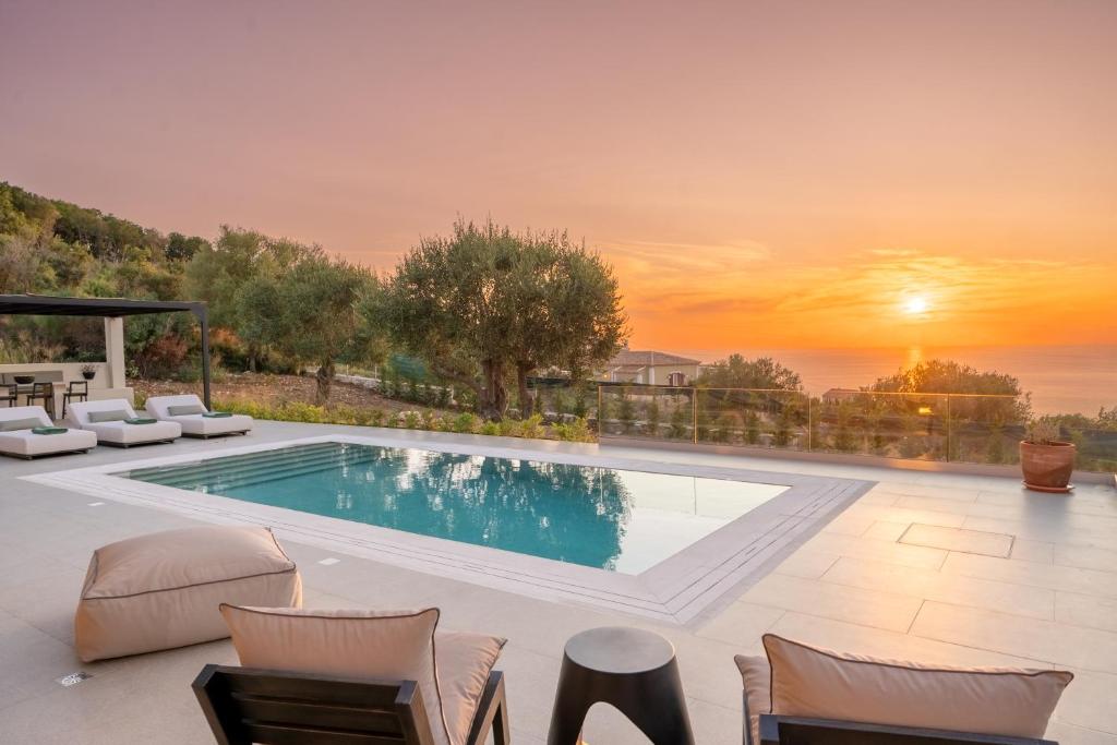 a pool with chairs and a sunset in the background at Horizon Retreat in Fiskardo