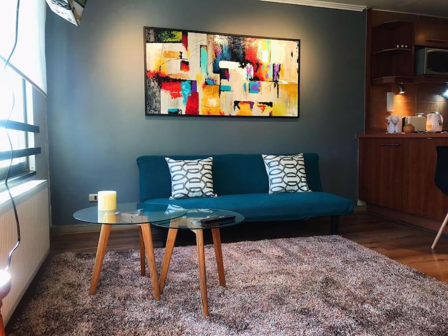 un salon avec un canapé bleu et une table dans l'établissement Bello y acogedor dpto cerca metro Baquedano 1303, à Santiago