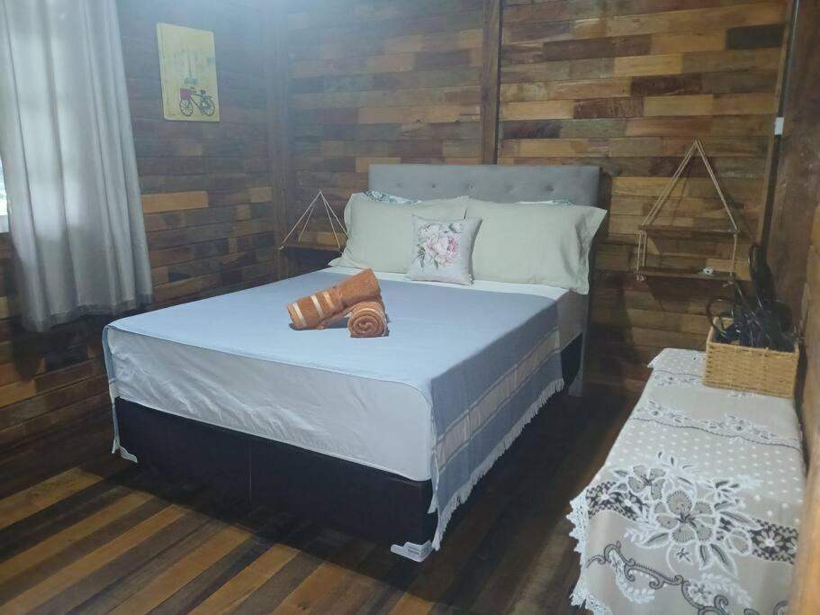 a bedroom with a bed with a wooden wall at Casa de campo Blumenau, 21km da vila germânica in Blumenau