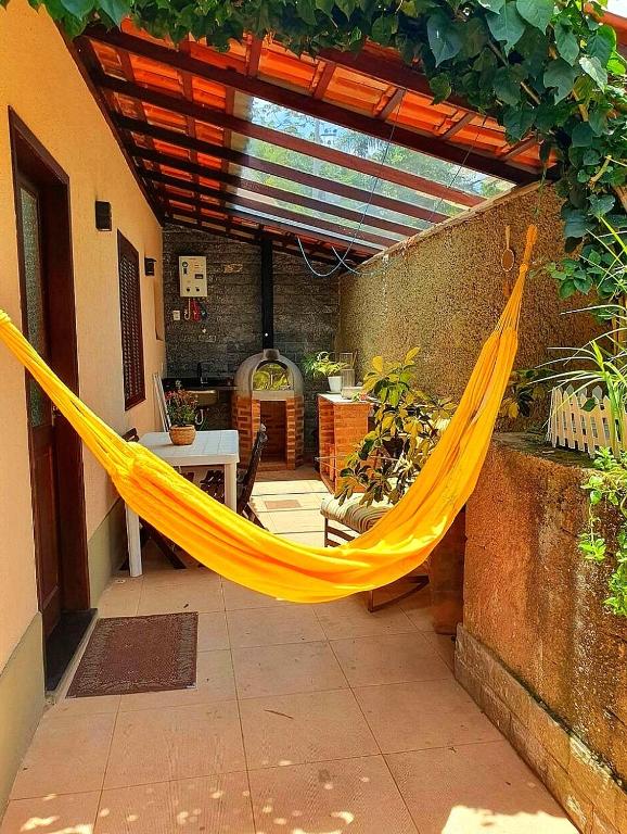 a yellow hammock hanging from an outdoor patio at Recanto de Itaipava - casa com forno de pizza a lenha, churrasqueira, pet friendly, equipada para até 6 pessoas, em meio à Natureza e próxima ao centro do bairro in Araras Petropolis