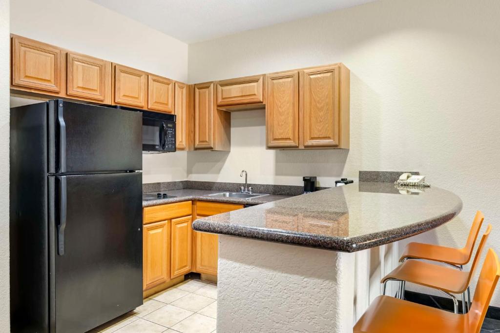 a kitchen with a black refrigerator and wooden cabinets at Best Western Lubbock West Inn & Suites in Lubbock