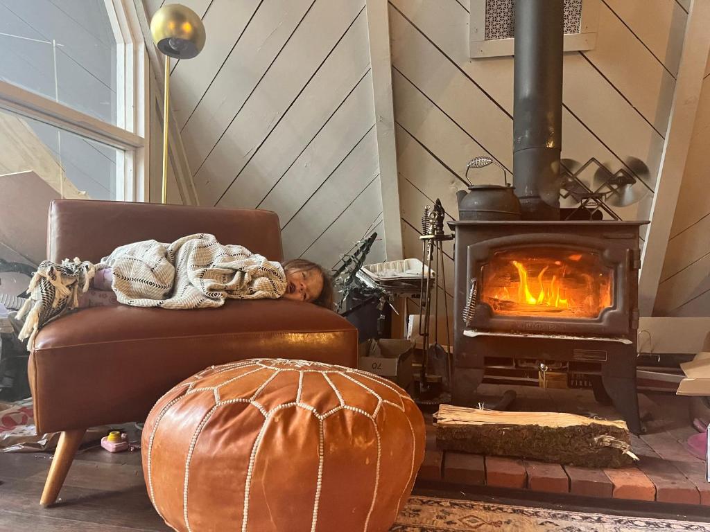 a man sleeping in a chair in front of a fireplace at Aframe of Mind Packwood in Packwood