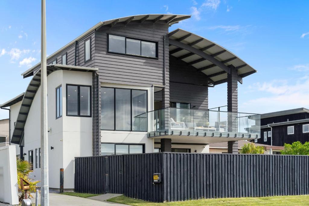 una casa moderna con un tetto curvo di Beachfront Paradise - Papamoa Beach Holiday Home a Papamoa
