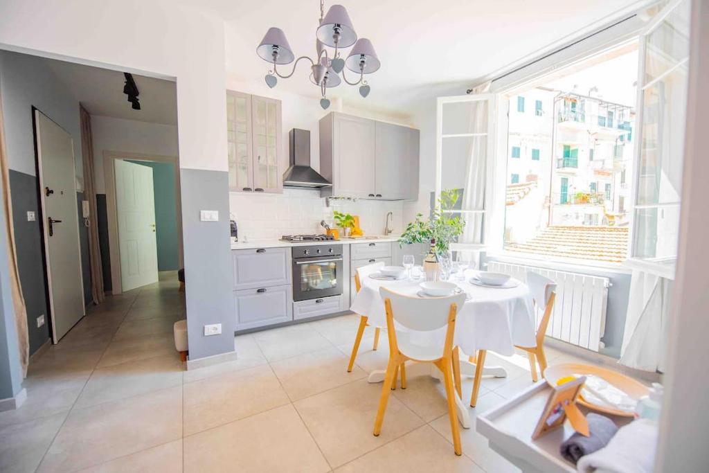 a kitchen with a white table and chairs and a window at Beach apartment in the center in Sanremo