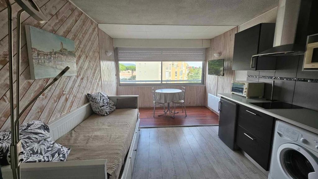 una piccola cucina con divano e tavolo di Studio plage du Grazel a Gruissan