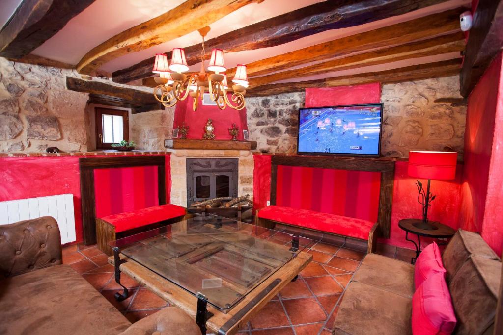 a living room with red furniture and a tv at Hotel Rural La Torre de Bisjueces in Bisjueces