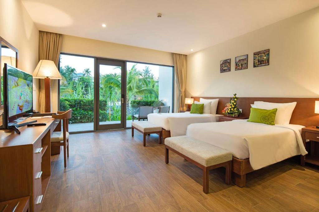 a hotel room with two beds and a desk at Cam Ranh Riviera Beach Resort & Spa in Cam Ranh